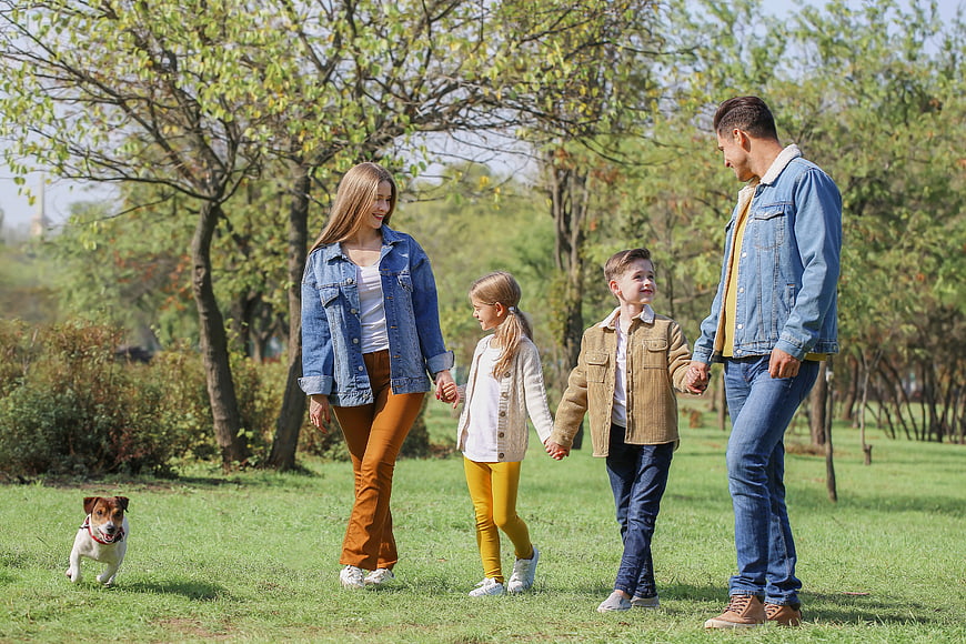 Happy family walking with dog in park