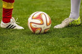Soccer ball between two players' feet on grass field
