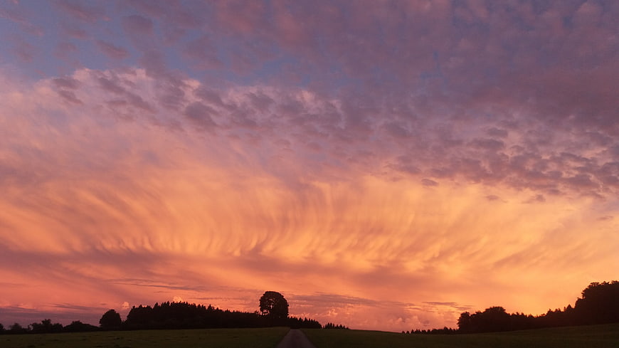 Dramatic sunset sky with textured clouds over rural landscape
