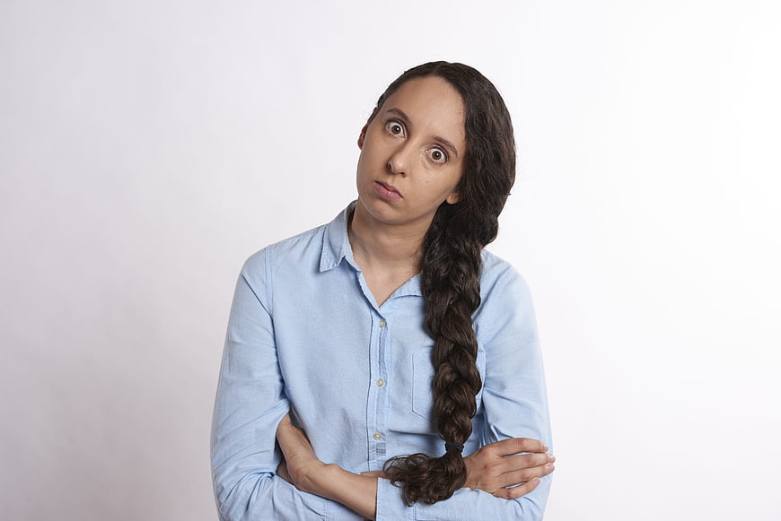 Frustrated young woman with crossed arms and scowl on white background