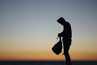 Silhouette of Man with Bag at Sunset