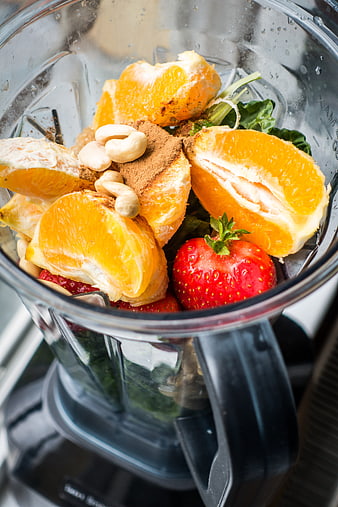 Fresh smoothie ingredients in blender with oranges and strawberries