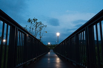 Empty wooden bridge at dusk with glowing street lamps