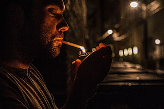 Man Lighting Cigarette at Night with Street Lights