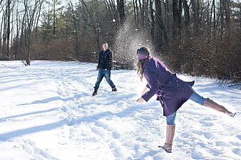 Young couple playing a snowball fight in a winter forest