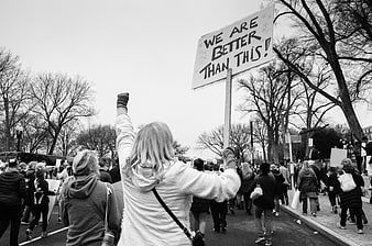 Woman holding protest sign reading We Are Better Than This