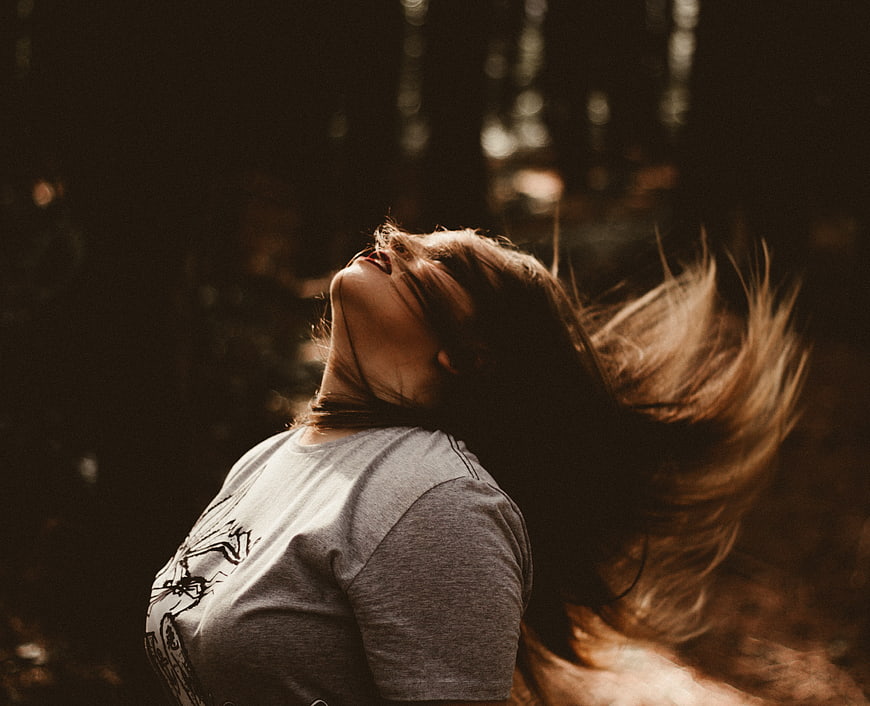 Woman with flowing hair in sunlit forest