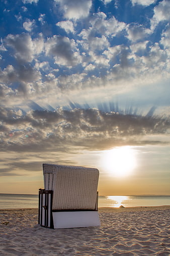 White Wicker Beach Bed on Sandy Shore at Sunset