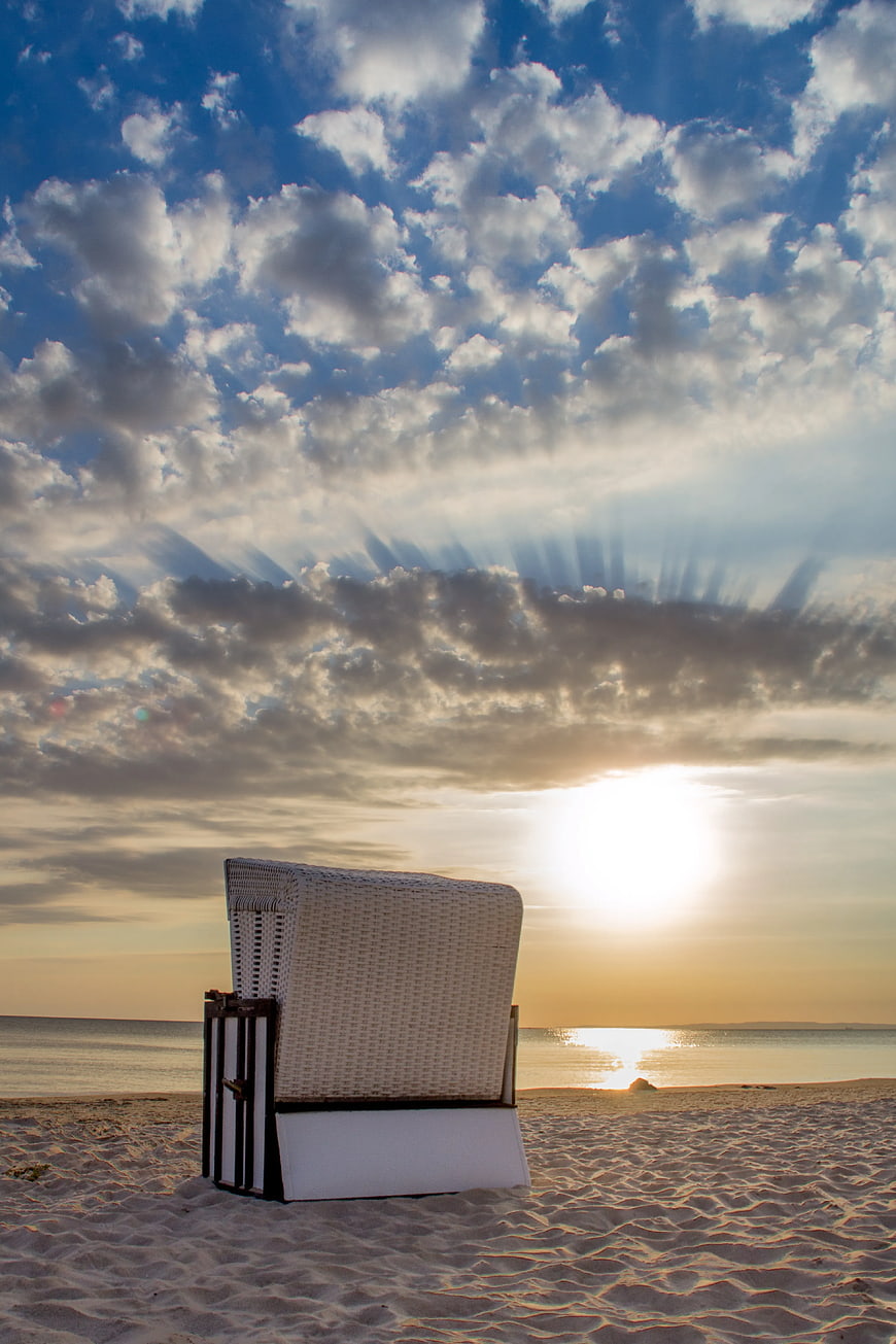 White Wicker Beach Bed on Sandy Shore at Sunset