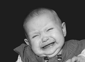 Black and white portrait of a crying infant with closed eyes