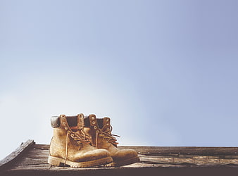 Worn Work Boots on Wooden Planks Against Blue Sky