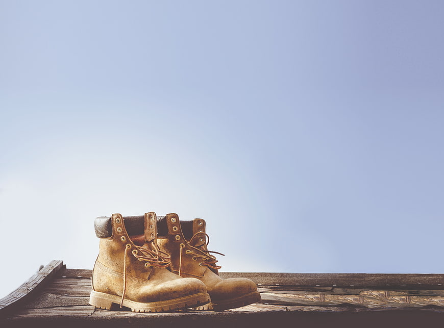 Worn Work Boots on Wooden Planks Against Blue Sky