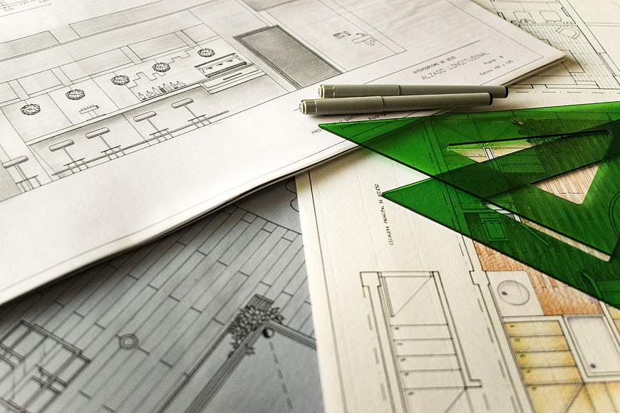 Architectural blueprints with green set square and pens