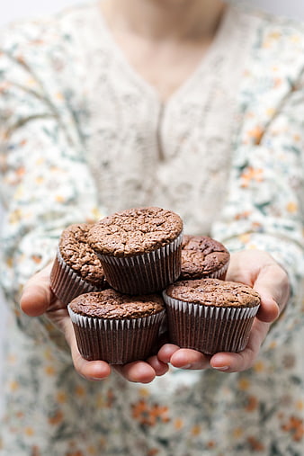 Woman holding homemade chocolate muffins in cupcake liners