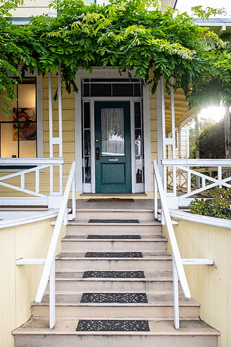 Charming yellow house entrance with green door and ivy