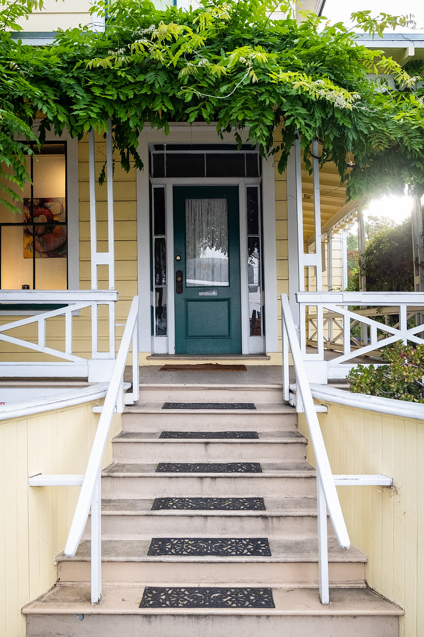 Charming yellow house entrance with green door and ivy