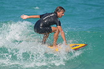 Man surfing on yellow board in turquoise ocean waves