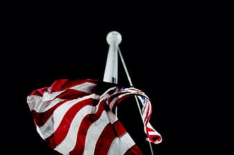 American flag waving on pole against black background