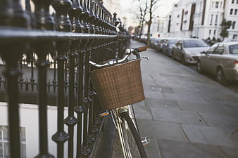 Silver Bicycle with Wicker Basket Leaning on Black Iron Fence