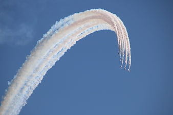 Airshow jets performing loop with smoke trails in blue sky