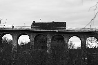 Black and white photo of stone viaduct with arches and pedestrian