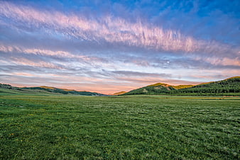 Vast Green Valley Landscape With Dramatic Pink Clouds At Dusk