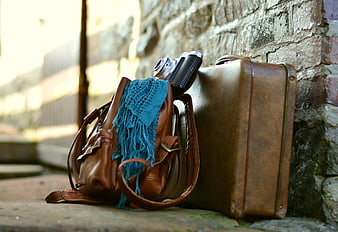 Vintage leather suitcase and camera against stone wall