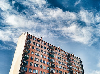 Low angle view of orange apartment building against blue sky