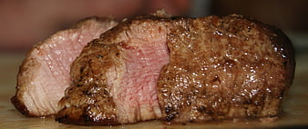 Close-up of juicy medium-rare sliced steak on wooden board