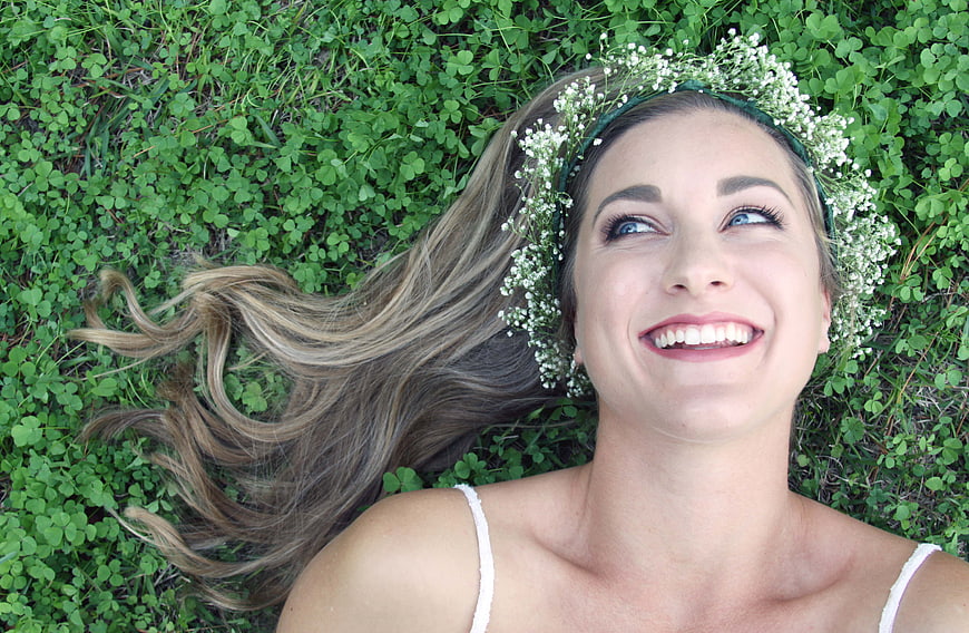 Happy Woman with Flower Crown Lying in Green Grass