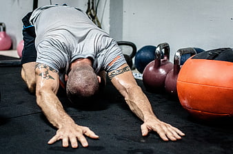 Man stretching in gym with kettlebells and medicine ball