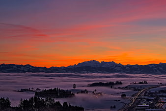 Snowy Mountain Range Above Sea of Fog at Sunset