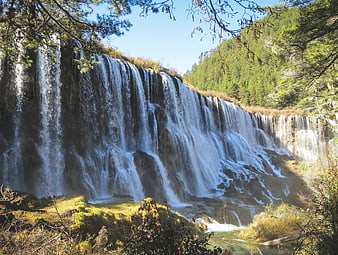 Wide Waterfall Cascading Through Forest in Jiuzhaigou