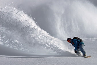 Snowboarder carving through deep powder snow on a mountain