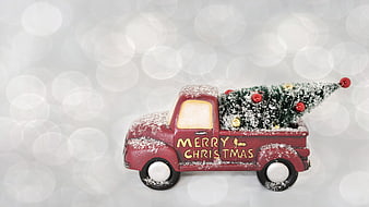Vintage red truck carrying Christmas tree with snow