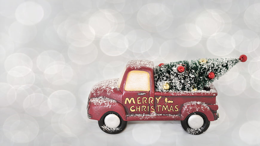Vintage red truck carrying Christmas tree with snow