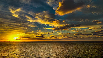 Dramatic Golden Sunset Over Ocean with Textured Clouds