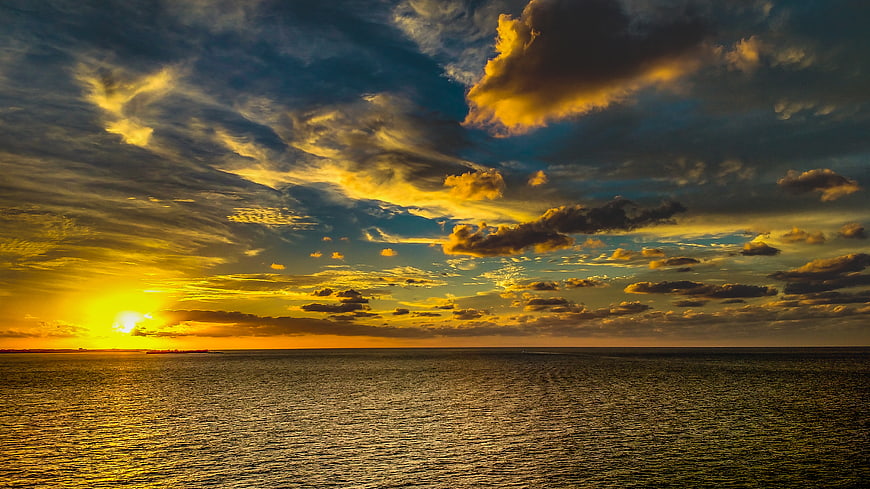 Dramatic Golden Sunset Over Ocean with Textured Clouds