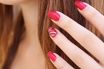 Close-up of red manicured nails with silver accent design
