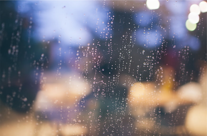 Raindrops on Window Glass with Blurred Bokeh Background
