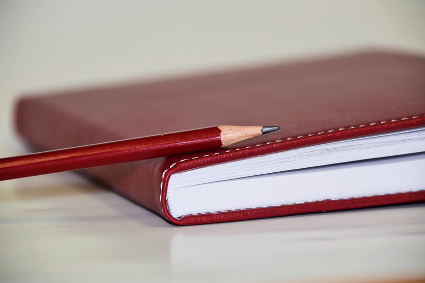Red Leather Notebook and Pencil on Desk