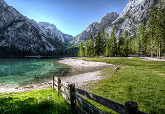 Scenic Alpine Lake with Wooden Fence and Mountain Peaks