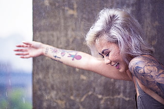 Blonde woman with tattoos laughing in the rain