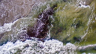 Aerial view of ocean waves crashing on rocky shore