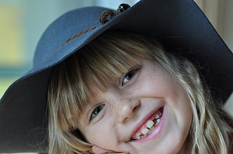Close-up portrait of smiling girl with freckles and hat