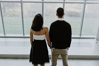 Couple standing by large windows looking at outdoor scenery