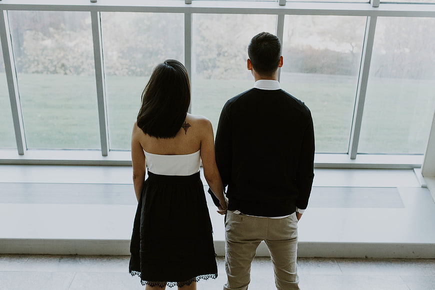 Couple standing by large windows looking at outdoor scenery