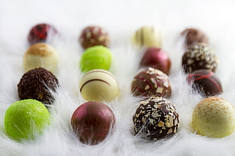 Assorted gourmet chocolate truffles on white fur background