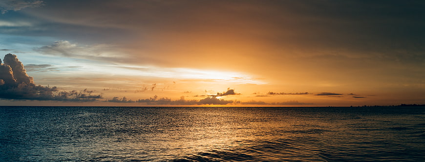 Panoramic Ocean Sunset with Golden Sky and Clouds