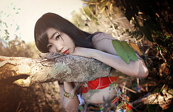 Woman Leaning on Tree Branch in Forest